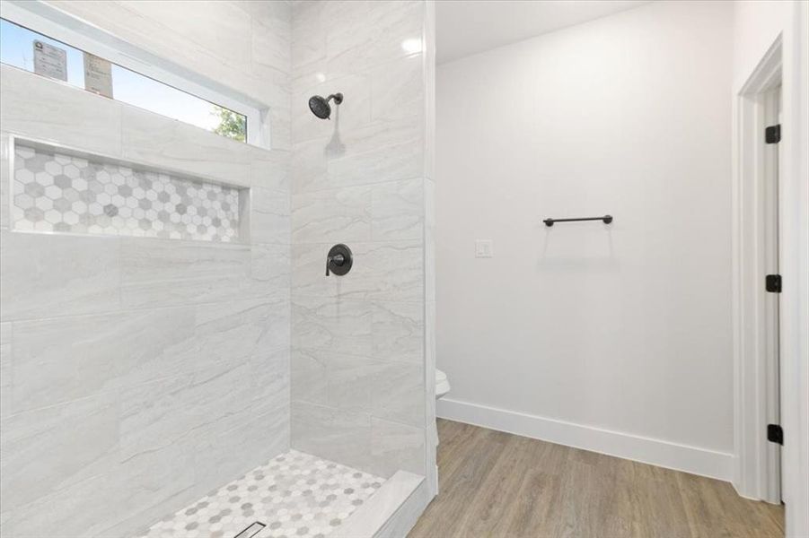 Bathroom with toilet, hardwood / wood-style flooring, and tiled shower