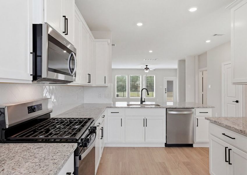Kitchen featuring a stainless range, white cabinetry, and granite countertops.