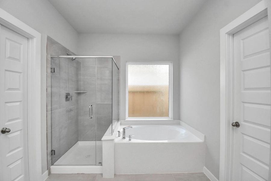 Escape to a spa-like oasis in this primary bathroom. Enjoy a walk-in shower with tile surround, a separate garden tub with custom detailing, and an elegant vanity featuring light countertops, modern hardware, and beautiful recessed lights. Experience luxury and relaxation in every detail. Sample photo of completed home with similar floor plan. Actual colors and selections may vary. Escape to a spa-like oasis in this primary bathroom. Enjoy a walk-in shower with tile surround, a separate garden tub with custom detailing, and an elegant vanity featuring light countertops, modern hardware, and beautiful recessed lights. Experience luxury and relaxation in every detail. Sample photo of completed home with similar floor plan. Actual colors and selections may vary.