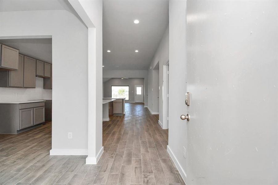 At the forefront, a large dedicated dining room. Luxurious details like premium flooring, custom paint, and expansive windows allowing an abundance of light. Sample photo of completed home. As-built color and selections may vary.