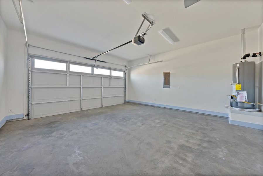 Garage featuring water heater, electric panel, and a garage door opener