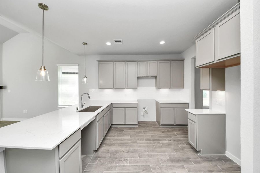 The kitchen is a culinary haven, featuring granite countertops, a tile backsplash, stainless steel appliances, 42” upper cabinets, and undercabinet lighting. Sample photo of completed home with similar floor plan. Actual colors and selections may vary. The kitchen is a culinary haven, featuring granite countertops, a tile backsplash, stainless steel appliances, 42” upper cabinets, and undercabinet lighting. Sample photo of completed home with similar floor plan. Actual colors and selections may vary.