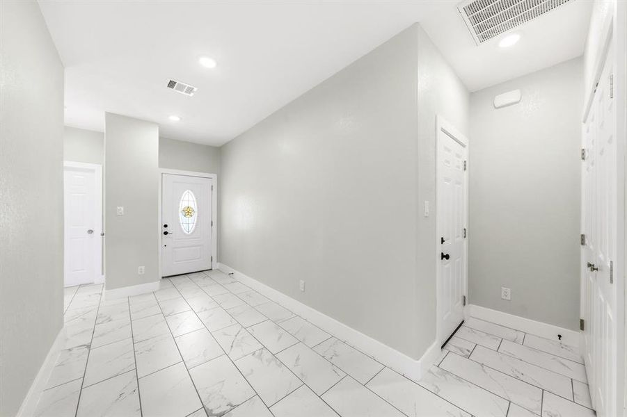 Entrance foyer featuring light marble finish flooring and recessed lighting