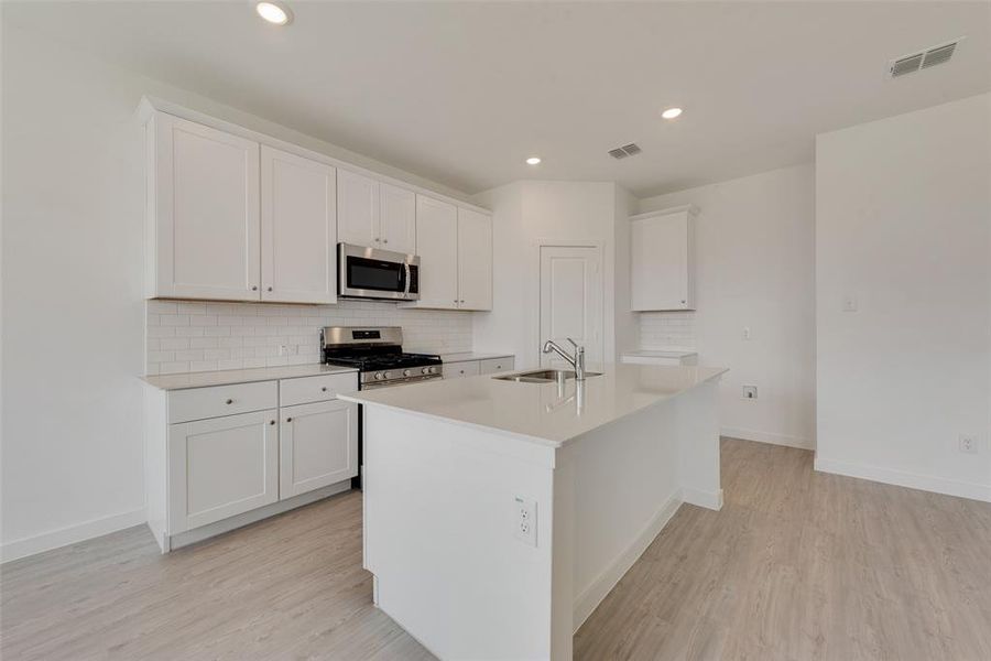 Kitchen featuring a kitchen island with sink, appliances with stainless steel finishes, sink, and white cabinetry