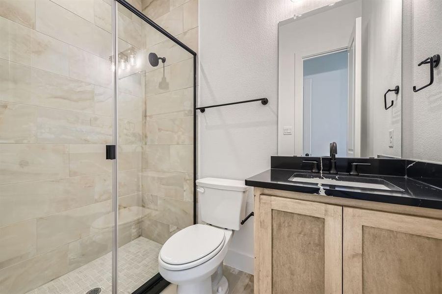 Bathroom featuring vanity, a shower with shower door, and toilet