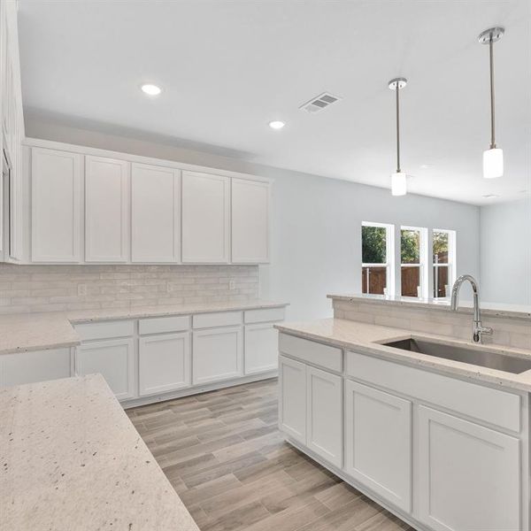 Kitchen featuring hanging light fixtures, sink, light hardwood / wood-style flooring, and white cabinets