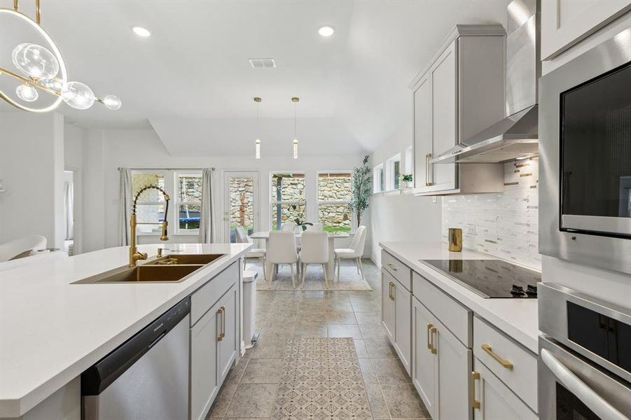 Modern kitchen featuring white cabinetry with gold-tone hardware, a gold-tone faucet, a double basin sink, and a built-in dishwasher