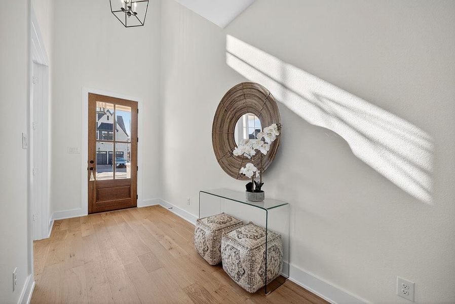 Entryway with wood finished floors, a high ceiling, and a chandelier Entryway with wood finished floors, a high ceiling, and a chandelier