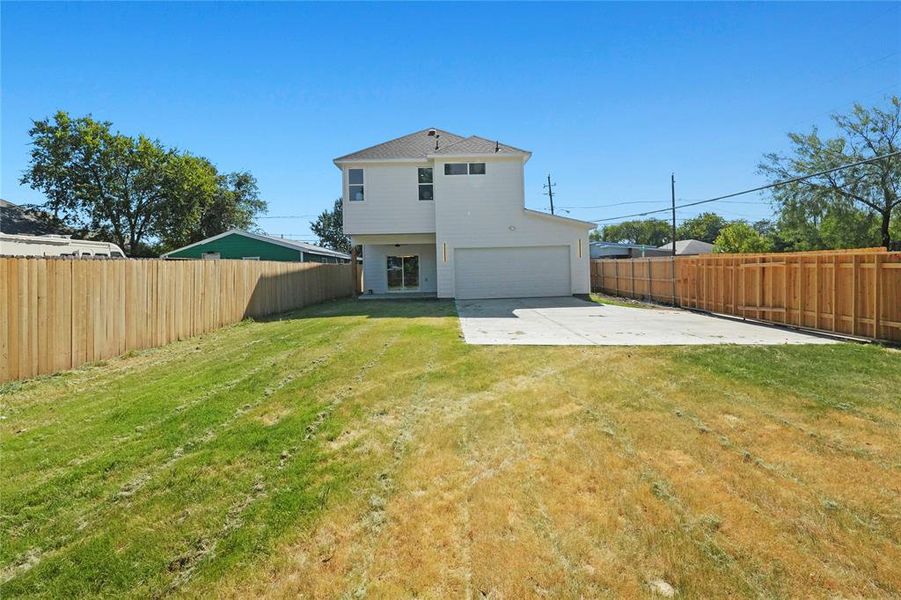 Back of house featuring a fenced backyard, concrete driveway, and an attached garage Back of house featuring a fenced backyard, concrete driveway, and an attached garage