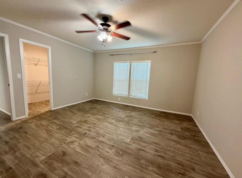 Spacious room featuring wood-finish flooring, neutral-toned walls, and white trim