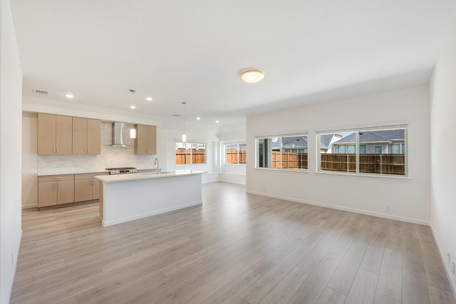 Open-concept living area and kitchen with light wood cabinets, center island, and hardwood floors Open-concept living area and kitchen with light wood cabinets, center island, and hardwood floors