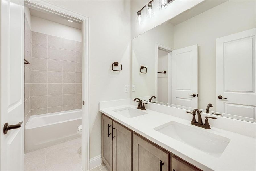 Full bathroom with double vanity, light tile patterned flooring, and bathing tub / shower combination Full bathroom with double vanity, light tile patterned flooring, and bathing tub / shower combination