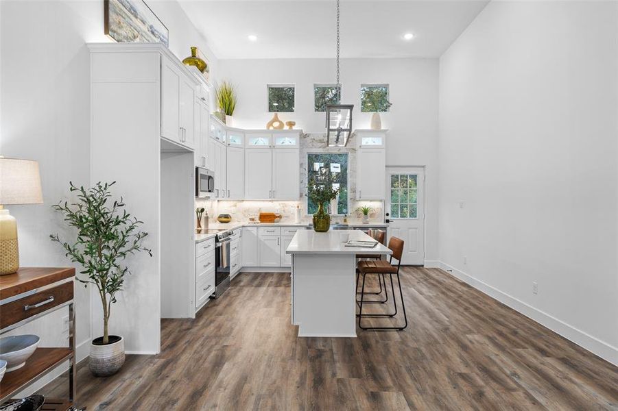 Kitchen with a center island, white cabinetry, stainless steel appliances, decorative light fixtures, and dark hardwood / wood-style flooring