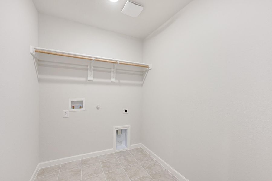 Laundry room with wall-mounted shelf, washer hookups, dryer outlet, and tile floor