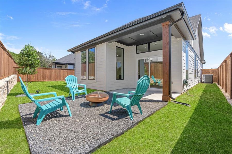 Back of property featuring a patio, a yard, an outdoor fire pit, and central AC unit