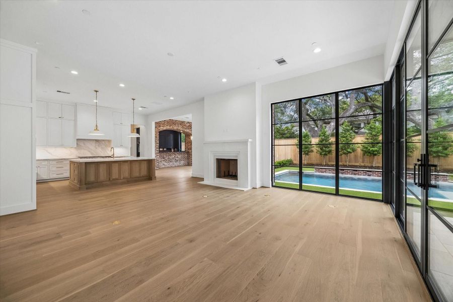Gorgeous windows provide ample natural light, creating an open and inviting atmosphere overlooking the pool and covered outdoor kitchen/living space.