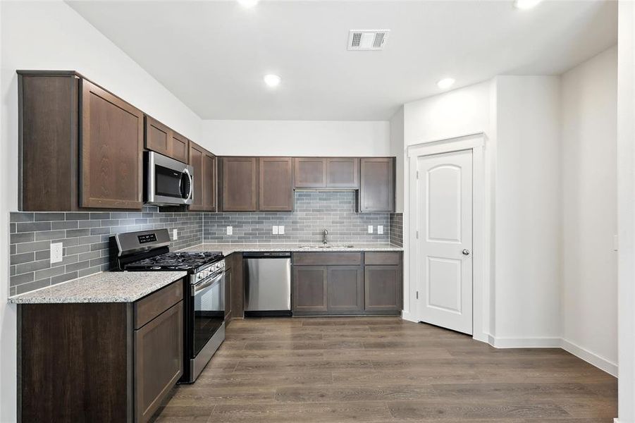 Kitchen featuring appliances with stainless steel finishes, dark brown cabinets, decorative backsplash, and recessed lighting Kitchen featuring appliances with stainless steel finishes, dark brown cabinets, decorative backsplash, and recessed lighting