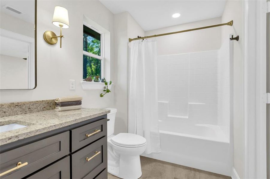 Full bathroom featuring vanity, shower / bath combo, and wood finished floors Full bathroom featuring vanity, shower / bath combo, and wood finished floors