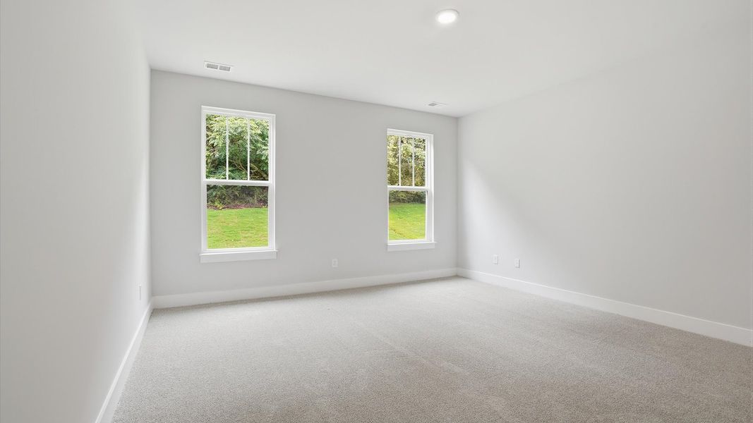 Serene and stylish primary bedroom featuring carpeted flooring and a thoughtful, modern layout