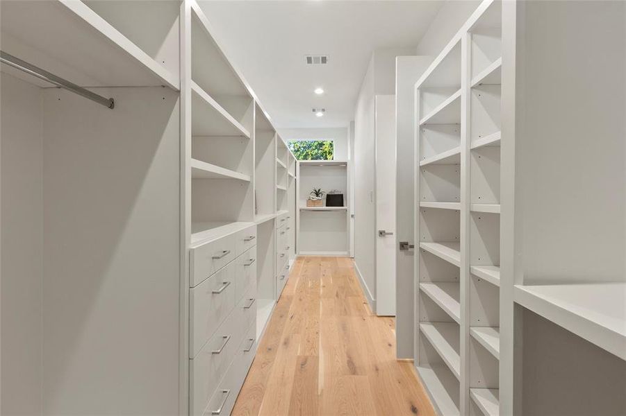 Huge primary bedroom closet with double entry filled with custom cabinetry