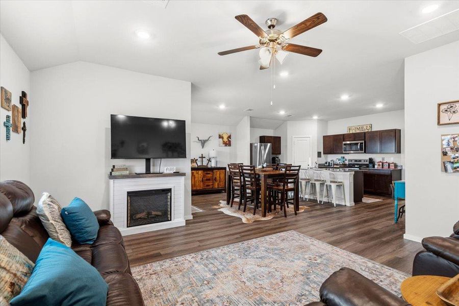 Living area featuring a ceiling fan, dark wood-style floors, a fireplace, recessed lighting, and lofted ceiling