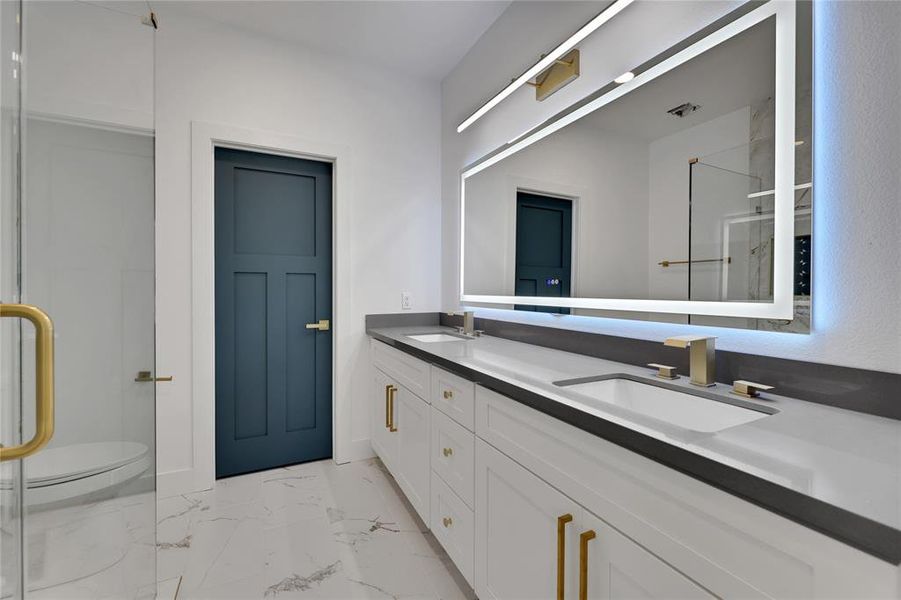 The primary bathroom has dual sinks along with a large lighted/heated mirror