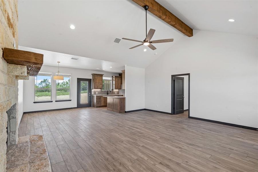 Unfurnished living room with beamed ceiling, light wood-type flooring, ceiling fan, recessed lighting, and high vaulted ceiling