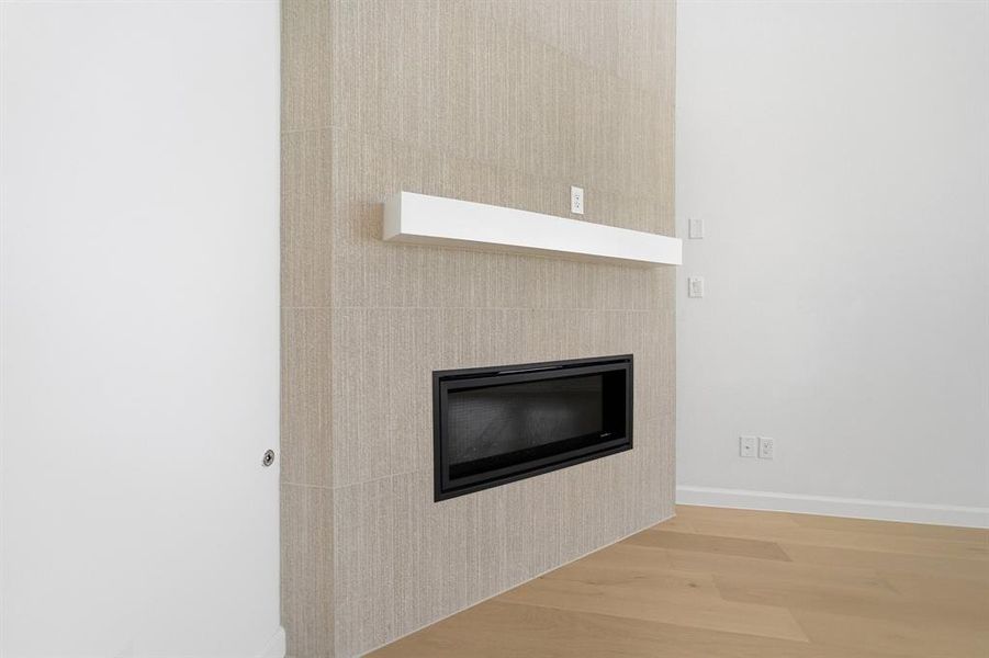 Modern fireplace feature wall with light-toned rectangular tile surround, a built-in linear electric fireplace, and a white floating mantel Modern fireplace feature wall with light-toned rectangular tile surround, a built-in linear electric fireplace, and a white floating mantel
