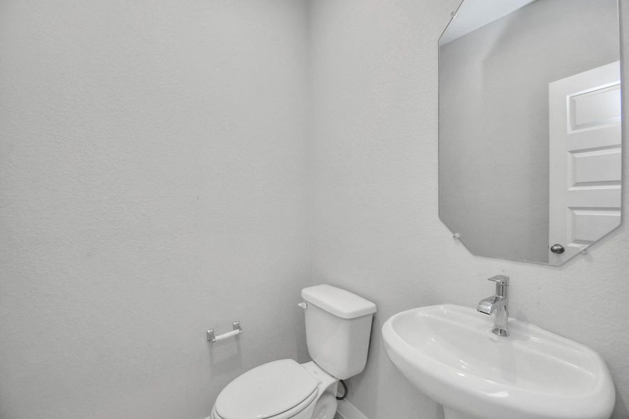 This half bathroom features a stylish pedestal sink, modern hardware, and bright recessed lighting, creating a sleek and inviting space. Sample photo of completed home with similar floor plan. Actual colors and selections may vary. This half bathroom features a stylish pedestal sink, modern hardware, and bright recessed lighting, creating a sleek and inviting space. Sample photo of completed home with similar floor plan. Actual colors and selections may vary.
