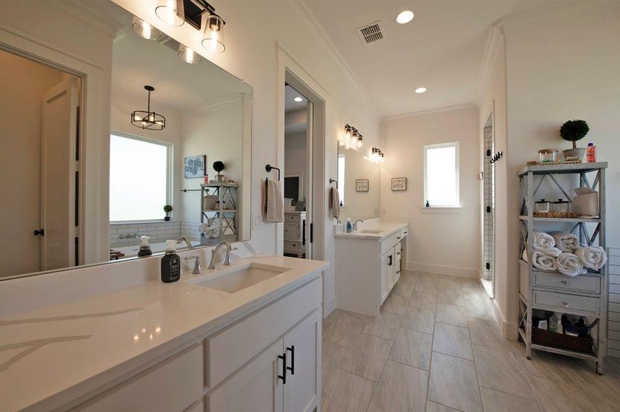 Full bathroom with crown molding, two vanities, a shower stall, and recessed lighting