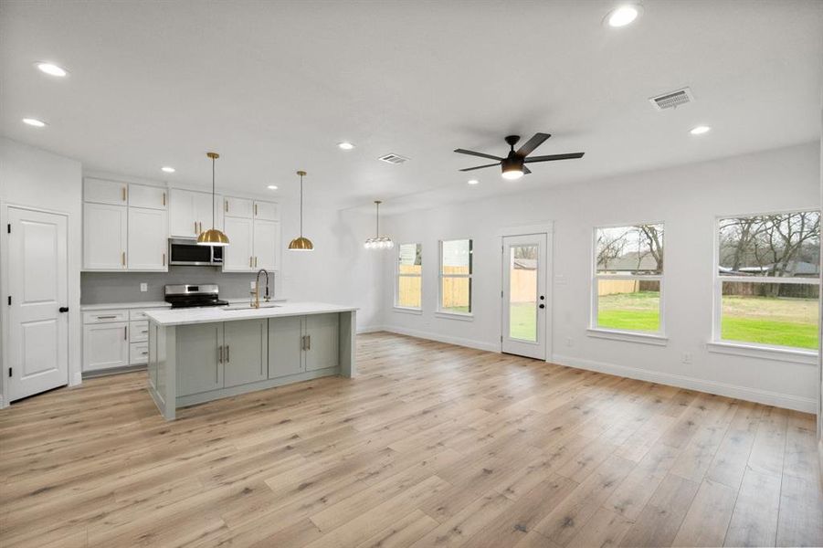 Kitchen with stainless steel appliances, recessed lighting, light countertops, open floor plan, and white cabinets