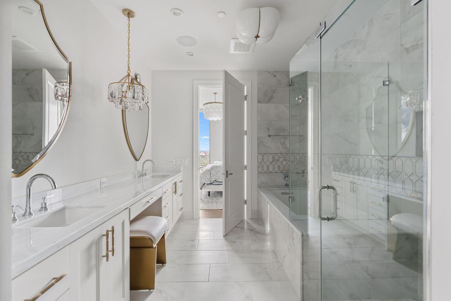 This elegant bathroom features a spacious dual-sink vanity, tile flooring, and a glass-enclosed shower and separate soaking tub. Crystal chandeliers add a touch of luxury, while the large mirror enhances the bright, airy feel. This elegant bathroom features a spacious dual-sink vanity, tile flooring, and a glass-enclosed shower and separate soaking tub. Crystal chandeliers add a touch of luxury, while the large mirror enhances the bright, airy feel.