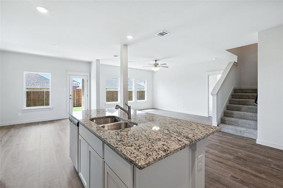 Kitchen with light stone countertops, light wood finished floors, a center island with sink, recessed lighting, and open floor plan Kitchen with light stone countertops, light wood finished floors, a center island with sink, recessed lighting, and open floor plan