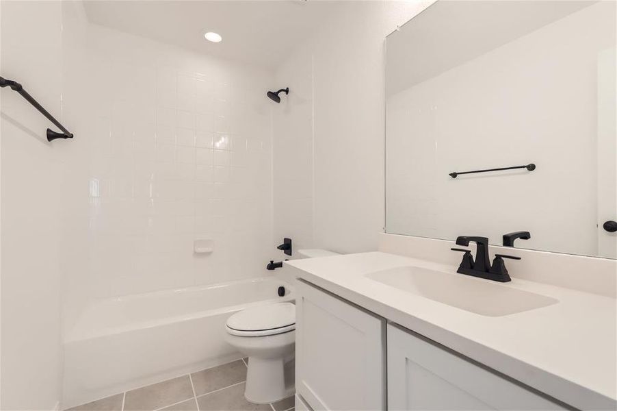 Full bathroom with tile flooring, tiled shower / bath, oversized vanity, and toilet