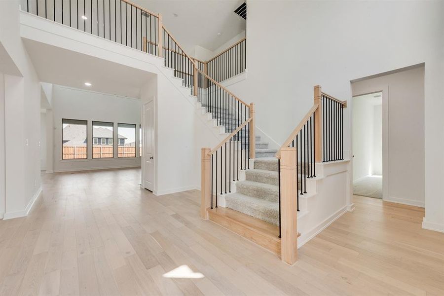 Staircase with wood finished floors, a towering ceiling, and recessed lighting Staircase with wood finished floors, a towering ceiling, and recessed lighting
