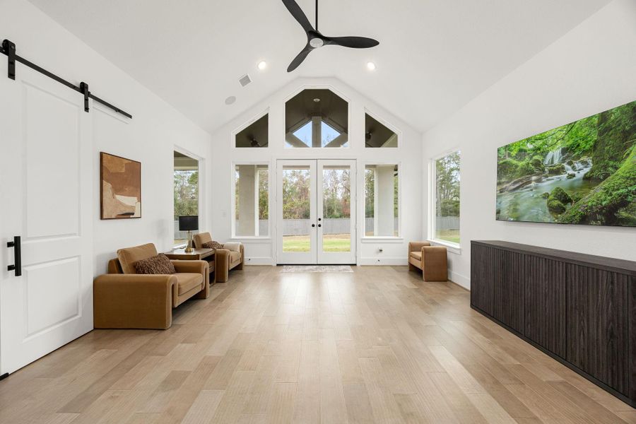 This versatile game room/ flex space offers endless possibilities. Spacious and light-filled game room with soaring vaulted ceilings and abundant natural light from a wall of windows and French doors overlooking the backyard.