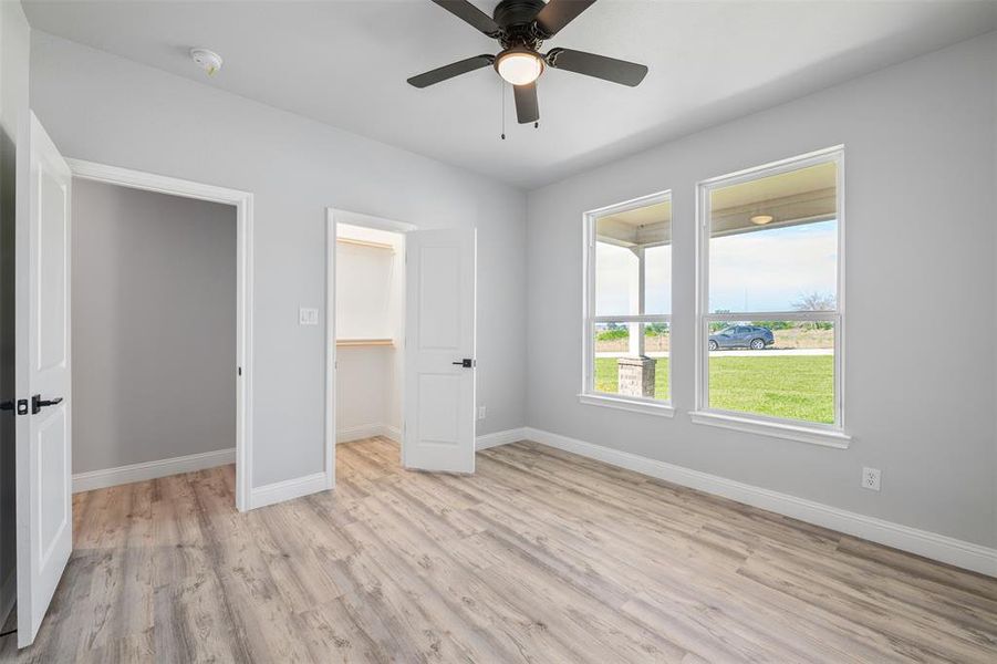 Unfurnished bedroom featuring light wood finished floors, a spacious closet, and ceiling fan Unfurnished bedroom featuring light wood finished floors, a spacious closet, and ceiling fan