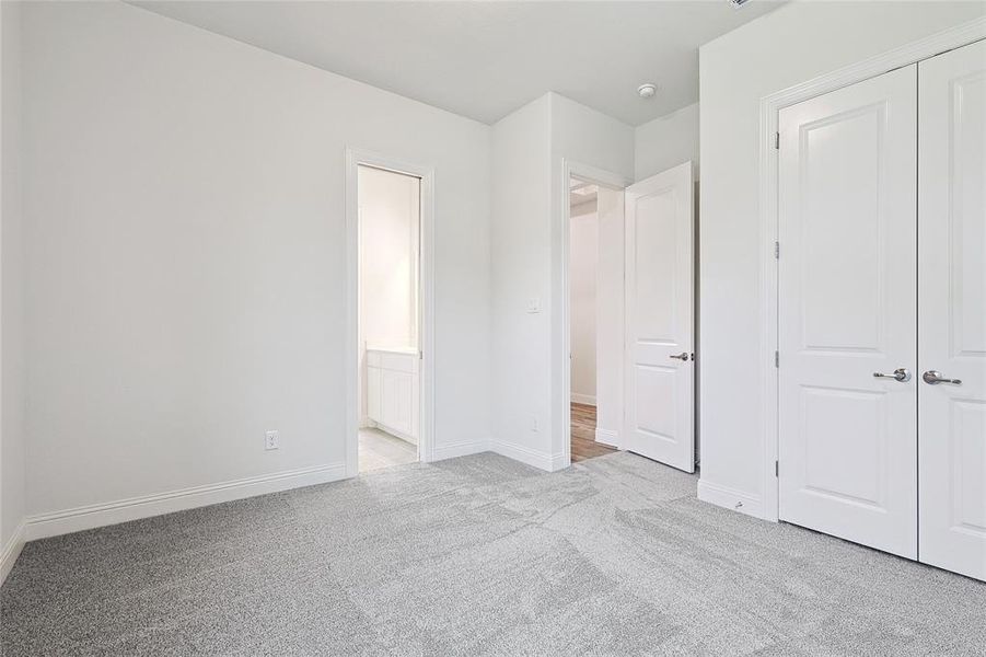 Unfurnished bedroom featuring light carpet and a closet