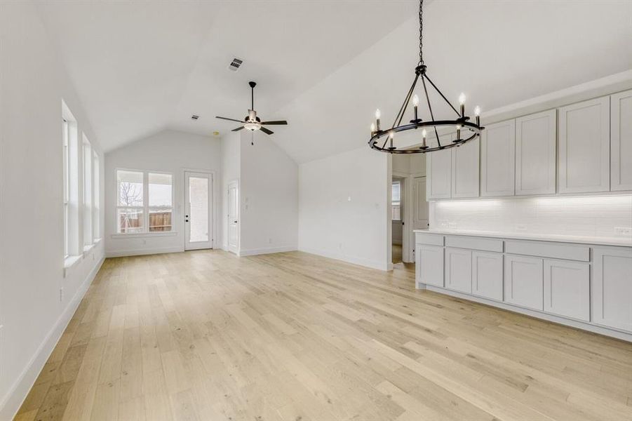Unfurnished living room featuring ceiling fan, hanging lights, and light wood-style flooring Unfurnished living room featuring ceiling fan, hanging lights, and light wood-style flooring