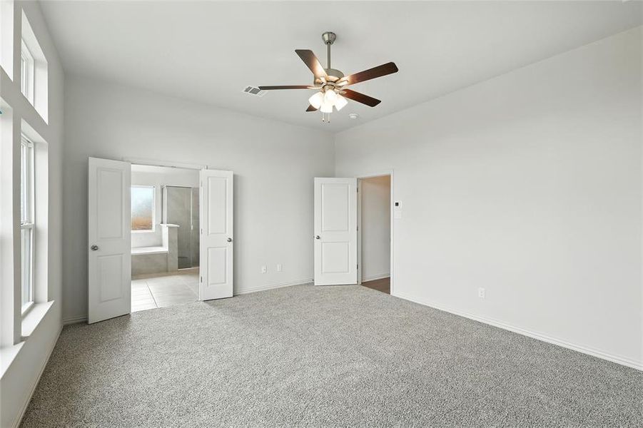 Unfurnished bedroom with carpet flooring, connected bathroom, and ceiling fan Unfurnished bedroom with carpet flooring, connected bathroom, and ceiling fan