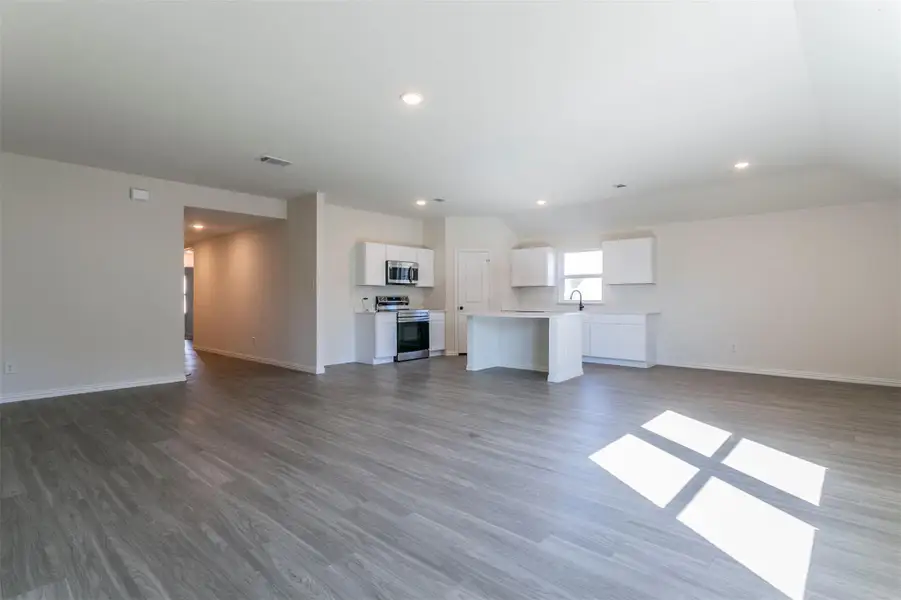 Unfurnished living room featuring recessed lighting, wood finished floors, visible vents, and baseboards Unfurnished living room featuring recessed lighting, wood finished floors, visible vents, and baseboards