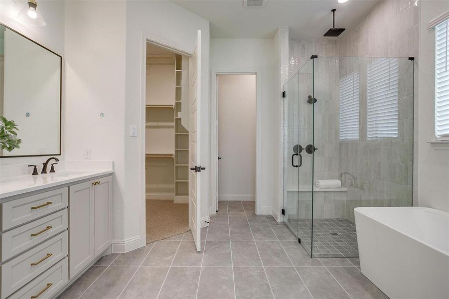 Primary Bathroom with vanity, walk in shower with standard shower head and rain head, freestanding tub, and large walk in shower