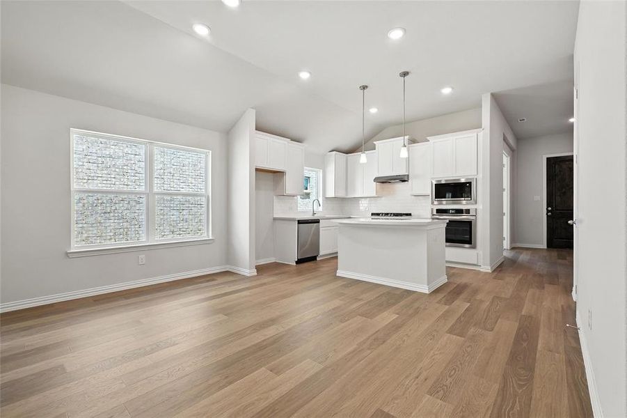 Kitchen featuring appliances with stainless steel finishes, lofted ceiling, tasteful backsplash, light countertops, and white cabinets Kitchen featuring appliances with stainless steel finishes, lofted ceiling, tasteful backsplash, light countertops, and white cabinets