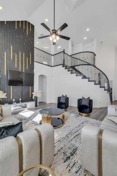 Living room with a towering ceiling, hardwood / wood-style flooring, and ceiling fan