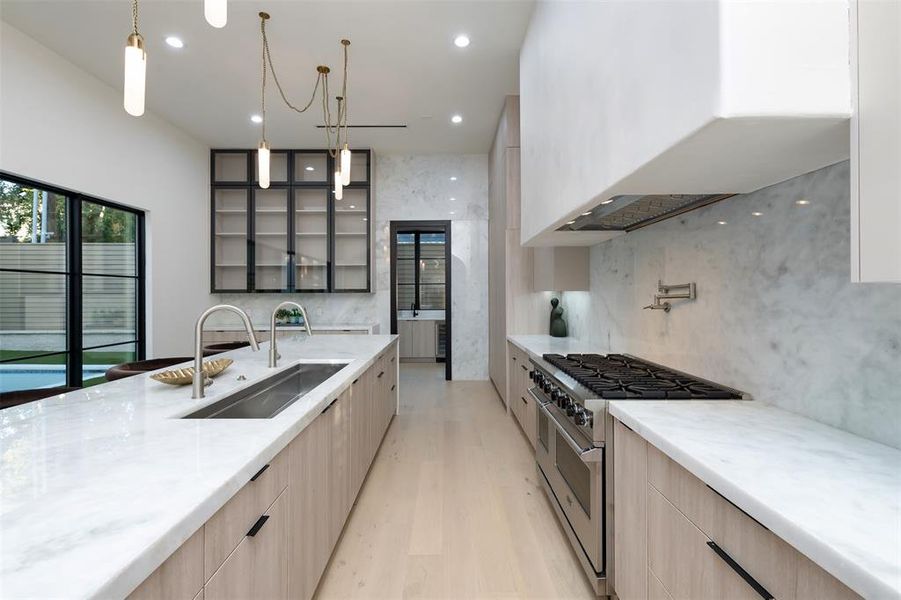 Kitchen featuring modern cabinets, light brown cabinetry, range with two ovens, decorative light fixtures, and recessed lighting