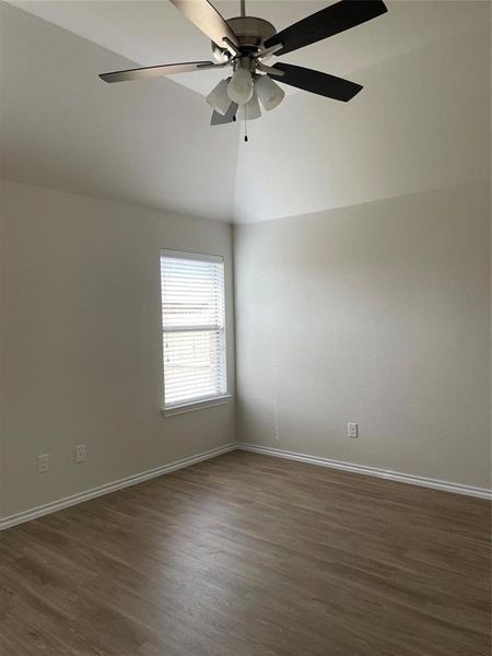 Spare room with dark wood-type flooring, ceiling fan, and vaulted ceiling