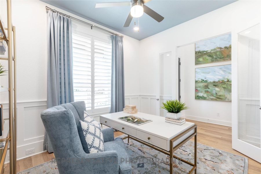 Office area featuring a wainscoted wall, light wood-type flooring, a decorative wall, and ceiling fan