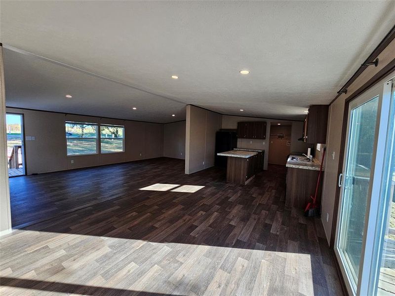 Kitchen featuring light countertops, dark brown cabinetry, dark wood-type flooring, open floor plan, and a center island Kitchen featuring light countertops, dark brown cabinetry, dark wood-type flooring, open floor plan, and a center island