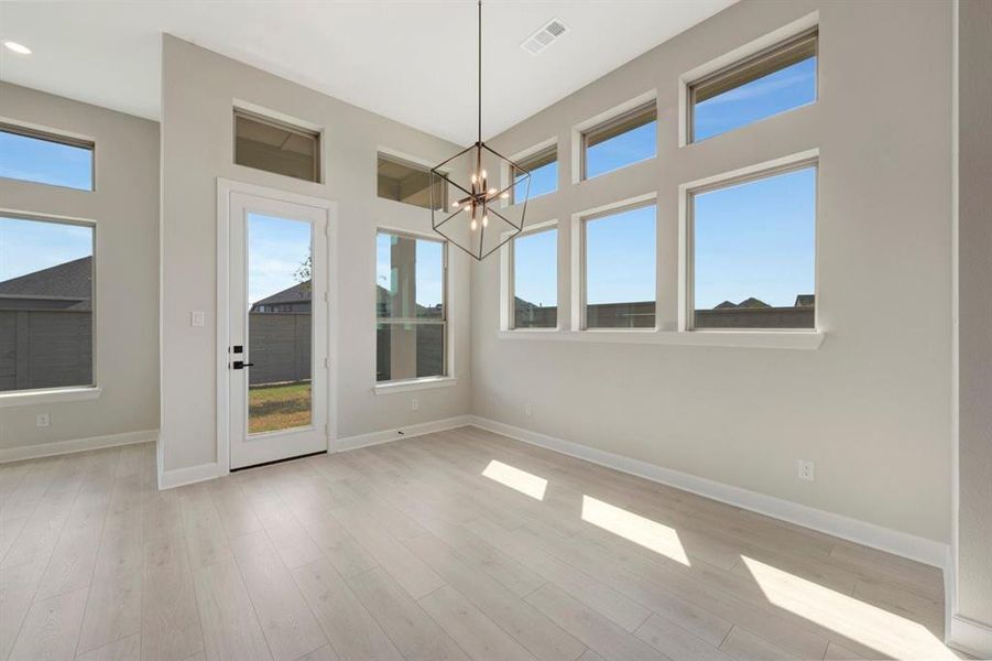 Spacious interior room featuring light wood-finish flooring and ample natural light from multiple windows