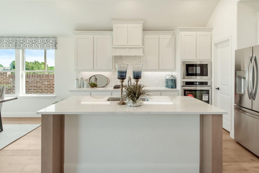 Kitchen with white cabinets, center island, stainless steel appliances, and light hardwood floors Kitchen with white cabinets, center island, stainless steel appliances, and light hardwood floors